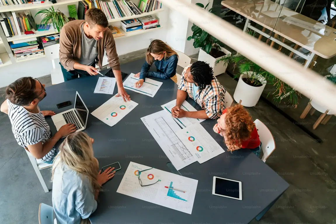 Equipo de producto reunido alrededor de una mesa con planos y gráficos