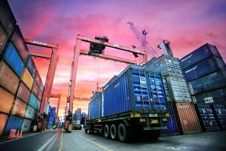Terminal portuaria con contenedores y camiones al atardecer