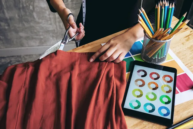 Diseñador cortando tela sobre la mesa de trabajo